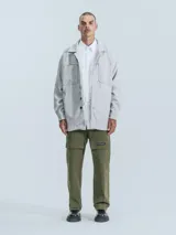 Campera gris melange de paño con cuello camisero, cierre frontal con botones a presión, bolsillos frontales y corte recto.