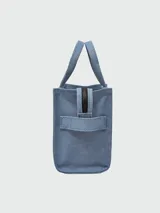 Bolso tote pequeño de lona color beige con estampado frontal en blanco con la leyenda "The Tote Bag Marc Jacobs". Tiene doble asa de mano y correa bandolera negra ajustable y extraíble.