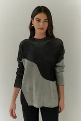 Buzo de punto con diseño geométrico en bloques de color gris y negro, de cuello redondo y mangas largas.