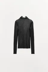 Top semitransparente tipo jersey confeccionado en hilatura de algodón 100%. Cuello alto y manga larga.