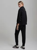 Buzo negro de corte oversize con cuello alto, mangas abullonadas, cierre lateral y hombros caídos.