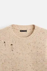 Sweater color beige con detalles de roturas y agujeros.