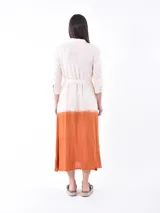 Vestido midi color crudo con efecto degradado color naranja en la parte inferior. Tiene corte camisero, cuello clásico, mangas 3/4 y cinturón de tela color naranja.