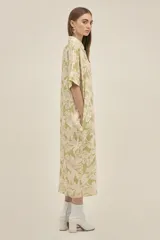 Vestido camisero largo de lino color verde claro con estampado de flores blancas, estilo oversize, con cuello camisero, mangas cortas, bolsillos laterales y botones de madera. Marca Polonio, hecho en Italia.