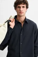 Camisa azul marino de corte regular fit, confeccionada en tejido de algodón con estructura. Tiene cuello solapa, manga larga con puños abotonados y cierre frontal con botones.