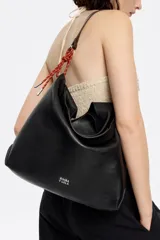 Bolso de mano negro con exterior de piel y estructura blanda. Incluye asa extraíble, bolsillo interior y etiqueta de tejido. Presenta logo metálico BIMBA Y LOLA con acabados metálicos plateados.
