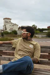 Remera color arena con cuello redondo y mangas cortas. Estampa pequeña de una margarita en el pecho.
