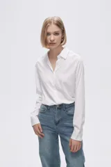 Camisa blanca de manga larga con cuello clásico y cierre frontal con botones. Corte recto y holgado.