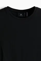 Remera negra de corte ajustado, con cuello redondo ribeteado y bajo recto. Confeccionada con tejido funcional COOLMAX®, una fibra exclusiva de poliéster de secado rápido que elimina la humedad y regula la temperatura corporal.