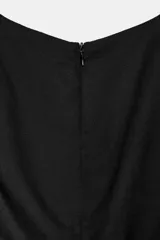 Vestido midi negro sin mangas, confeccionado en hilatura de lino. Presenta cuello redondo y falda evasé. Cierre trasero con cremallera oculta.