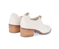 Zapato de cuero texturizado color hueso, con puntera redondeada, cierre con hebilla dorada y taco cuadrado de madera.