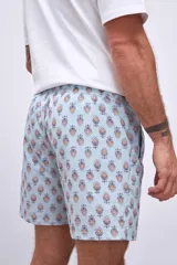 Short de baño celeste con estampado de flores rojas y hojas verdes.