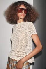 Top color crema de punto calado con cuello redondo y mangas cortas.