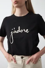 Remera blanca de algodón de manga corta, con cuello redondo y bordado frontal en hilo color beige claro con la palabra "J'adore" en tipografía cursiva.