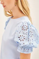 Remera blanca de algodón con mangas balloon de broderie, cuello redondo y tajos laterales.