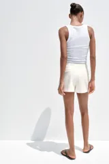 Falda pantalón corta color blanco, de tiro medio con abertura en el delantero y cierre lateral con cremallera.