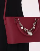 Cartera tipo city de cuerina color bordó, con doble asa corta y correa larga regulable. Incluye charm decorativo con cadena plateada y dijes colgantes.