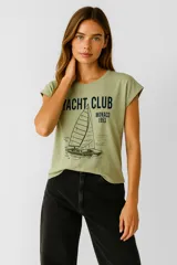 Remera verde con estampado de un velero y texto en color negro.