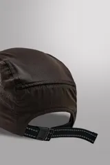 Gorra marrón de siete paneles de tejido técnico con perforaciones, visera y ajuste elástico en la parte posterior.
