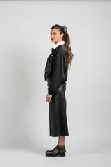 Falda larga de cuero negro, confeccionada con paneles rectangulares, de corte recto y cierre trasero.