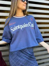 Remera azul con estampado frontal con el texto "Saintpain Club" en blanco y una estrella roja.