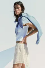 Falda corta de encaje color crema con forro interior. Presenta cintura elástica y bajo asimétrico con terminación en picos.