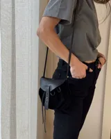 Bandolera negra de cuero gamuzado con solapa de cuero liso y cierre con tira de cuero.