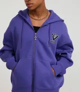 Canguro de algodón con felpa en color lila, con capucha ajustable, cierre frontal de cremallera y bolsillos delanteros. Presenta estampados de lettering en la espalda con diseños de estilo urbano.