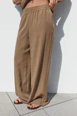 Pantalón marrón de tiro alto con cintura elástica, bolsillos delanteros y pernera ancha.