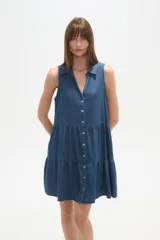 Vestido gris de algodón, largo hasta la rodilla, con cuello camisero, sin mangas, cierre frontal de botones blancos y falda con volados.