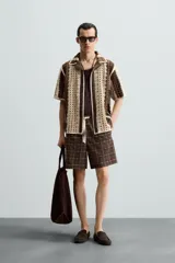 Camisa de hombre de corte relajado, confeccionada en tejido de crochet con estructura abierta. Presenta cuello bowling, manga corta y cierre frontal con botones.