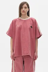 Remera oversized de denim color rosa lavado, con mangas caídas, cuello a contratono color crema y bordados en el frente.
