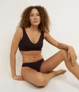 Soutien tipo bralette color gris, confeccionado en poliamida con acabado seamless y breteles anchos fijos. Presenta escote en V y una pequeña etiqueta con el logo "lov" en la parte frontal inferior.