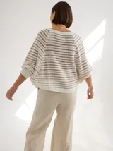 Buzo tipo poncho con mangas, tejido de punto color celeste con rayas horizontales marrones.