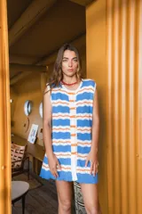 Vestido corto tejido a crochet con rayas horizontales en color celeste, blanco y naranja. Tiene cuello redondo, corte recto y cierre frontal con botones a tono.