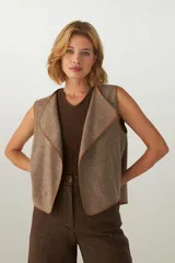 Chaleco marrón con solapas amplias y terminaciones envivadas. Diseño reversible y sin mangas.