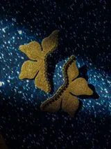 Par de aros dorados con forma de flor de siete centímetros de alto y detalle de strass.