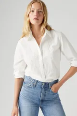 Camisa blanca de manga larga con bordado floral en el frente y detalle de puntilla en los puños.