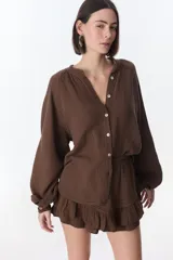 Camisa beige de manga larga con botones y detalles de encaje.