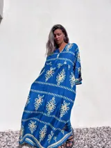Vestido túnica largo color azul con estampado floral en color crema, mangas 3/4 y escote en V.