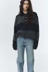 Sweater de punto grueso con diseño de bloques horizontales en tonos de gris y negro jaspeado. Posee cuello polo negro con tres botones de nácar.
