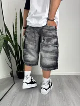 Bermuda de jean gris con efecto desgastado, corte holgado, largo a la rodilla y estampado con la frase "The Legend" en el bolsillo trasero.
