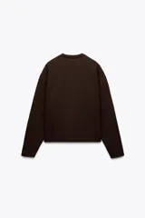 Sweater color crema de tejido suave, con cuello redondo en rib y mangas largas sin costuras.