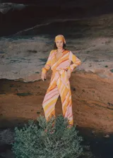 Pantalón de poliéster con estampado de rayas diagonales en tonos naranja, amarillo, rosa y blanco. Incluye cinturón de la misma tela.