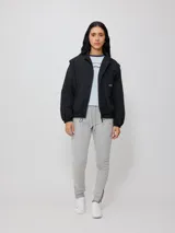 Campera negra tipo rompevientos de nylon con cierre frontal y bolsillos laterales.