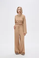 Pantalón de calce ancho y tiro alto, color beige con textura.