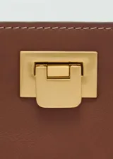Bolso tipo bucket negro con asa corta y cierre metálico dorado.