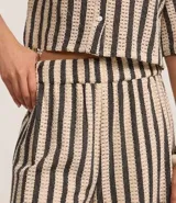 Pantalón recto de punto con rayas verticales en tonos beige y negro. Cuenta con cintura elástica y forro interior.