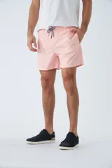 Short de baño azul con estampado de hojas y flores en blanco. Tiene cintura elástica con cordón ajustable, dos bolsillos laterales y uno trasero.