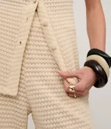 Pantalón de mujer color crema, de punto texturizado con efecto gofre o waffle, corte recto y pierna ancha.